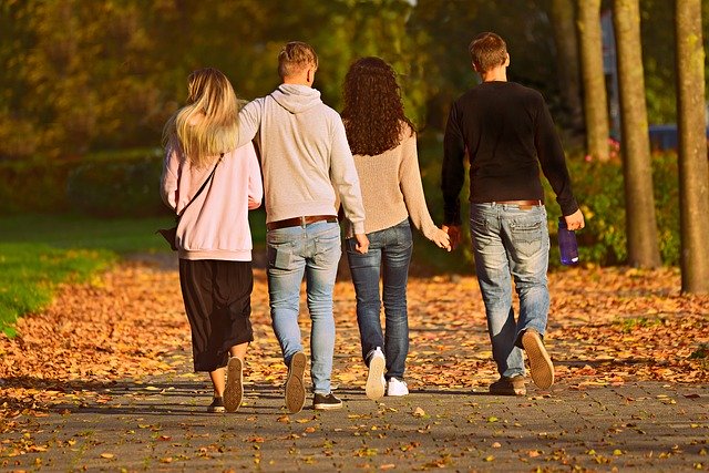 two couples walking in the park autumn leafs